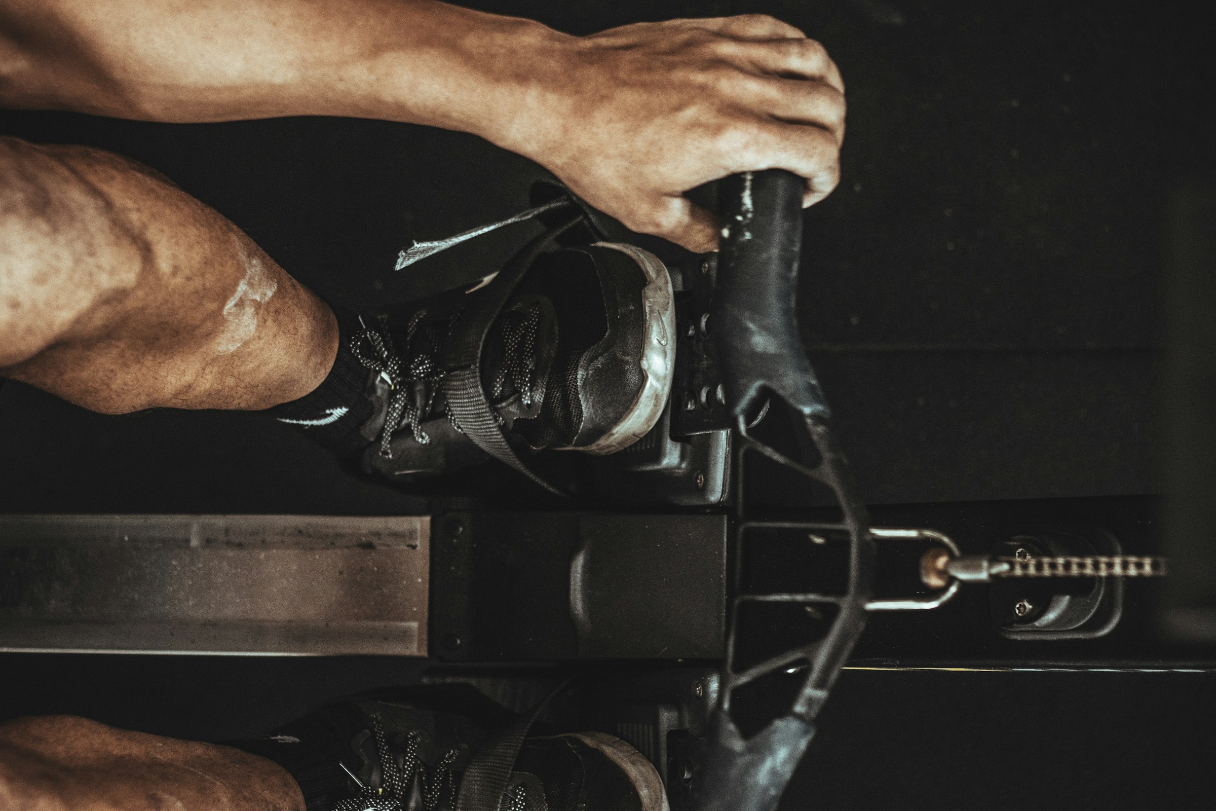 Hands on the handles of an exercise bike in low light