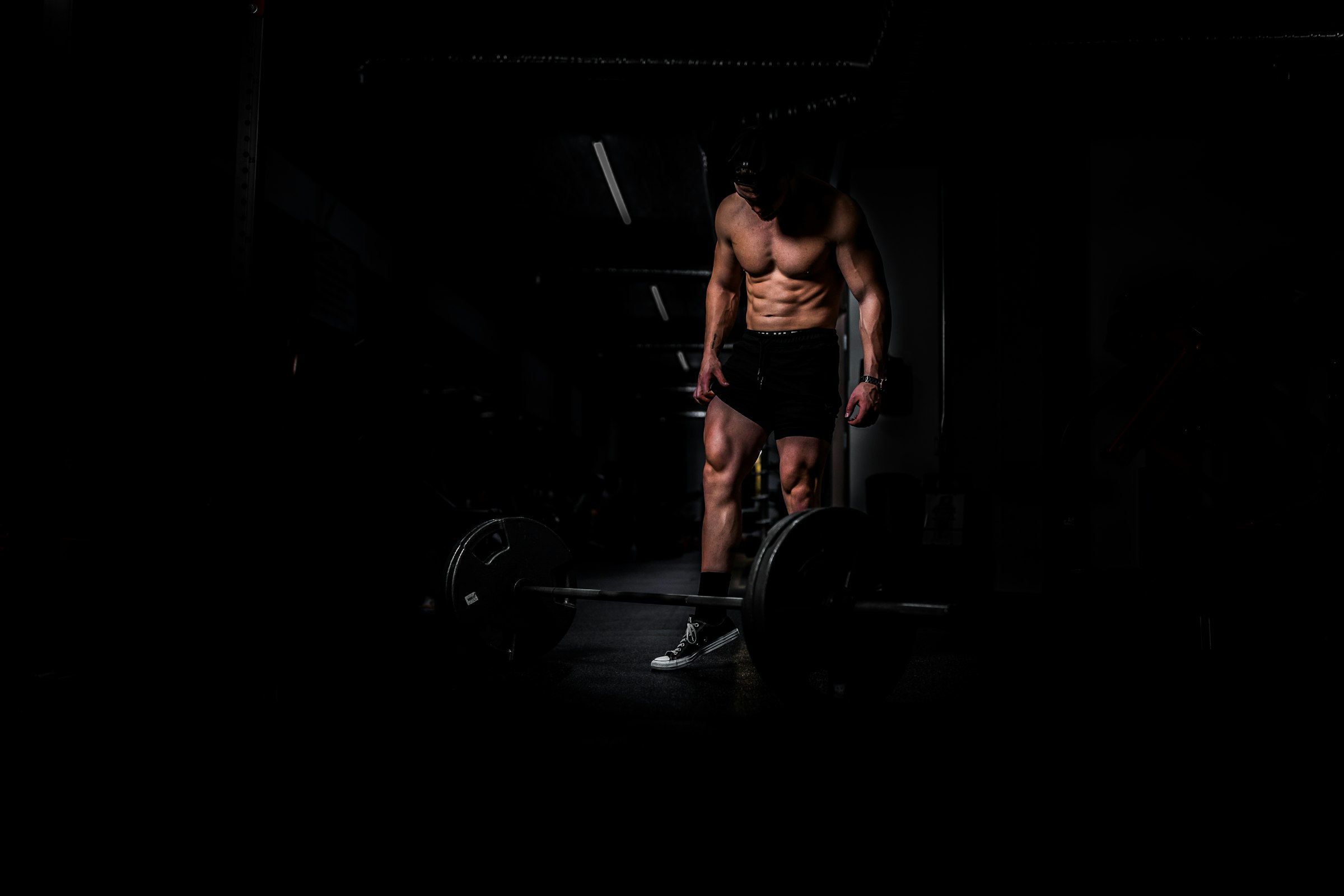 A lifter standing over a barbell in a dark gym