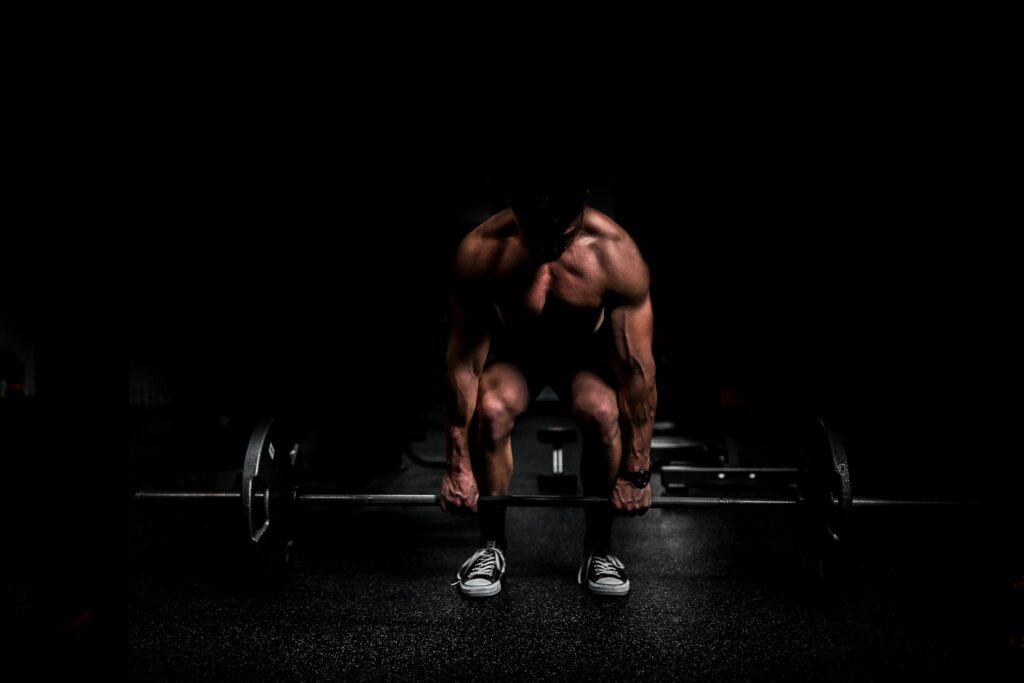 A lifter bracing over a barbell under a single light