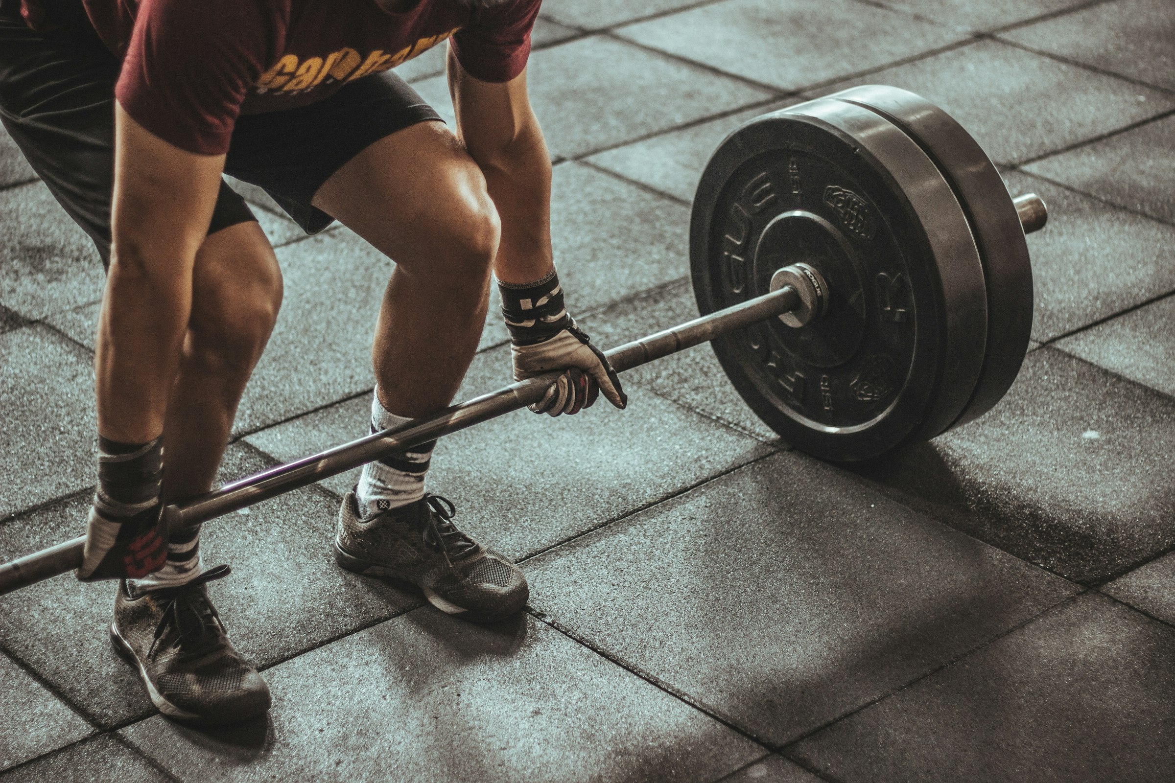 A lifter pulling a heavy barbell off a rubber gym floor