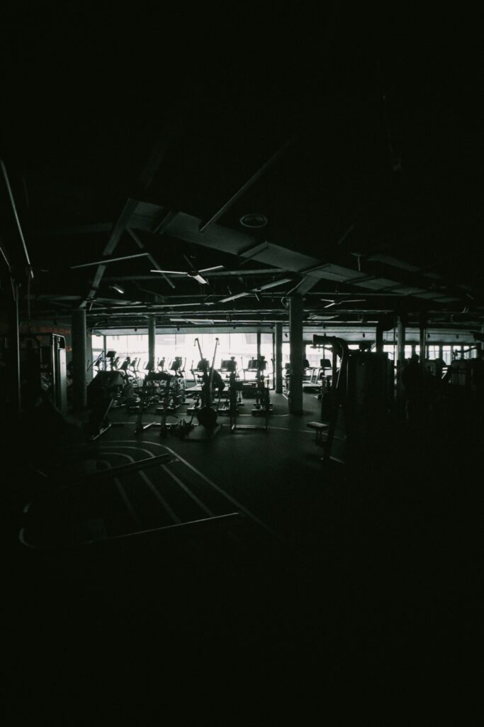 A dim gym floor with tall windows at the far end