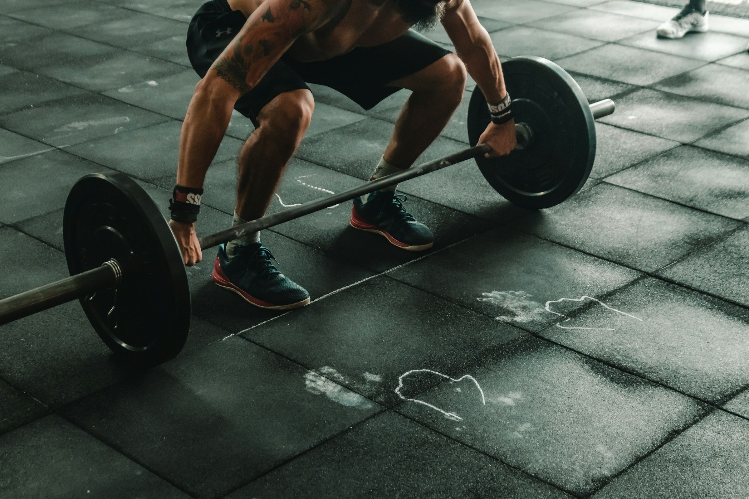 A lifter setting up over a loaded barbell on a chalk-marked rubber floor