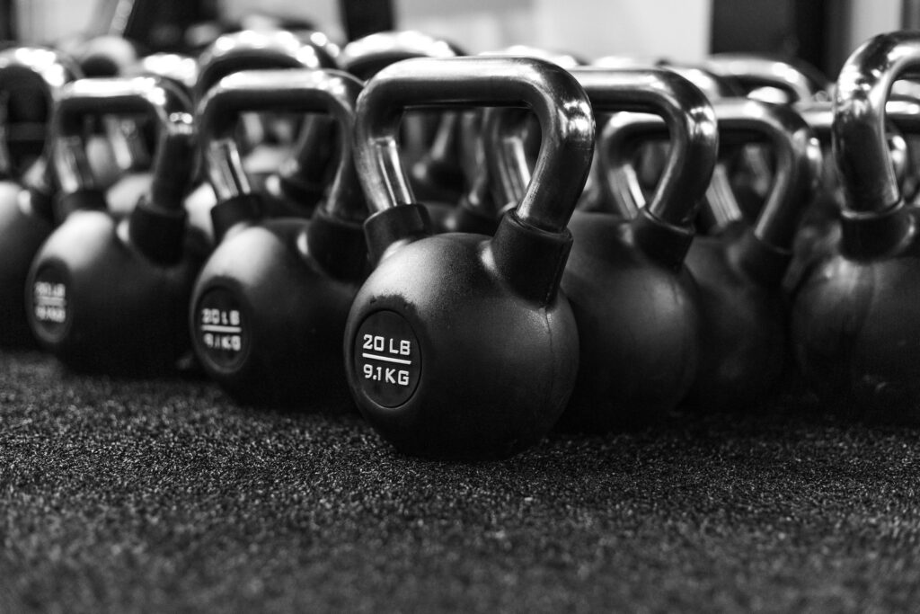 Rows of black kettlebells on a gym floor, in black and white