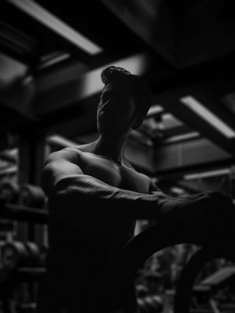 A lifter resting between sets in a dim gym, in black and white