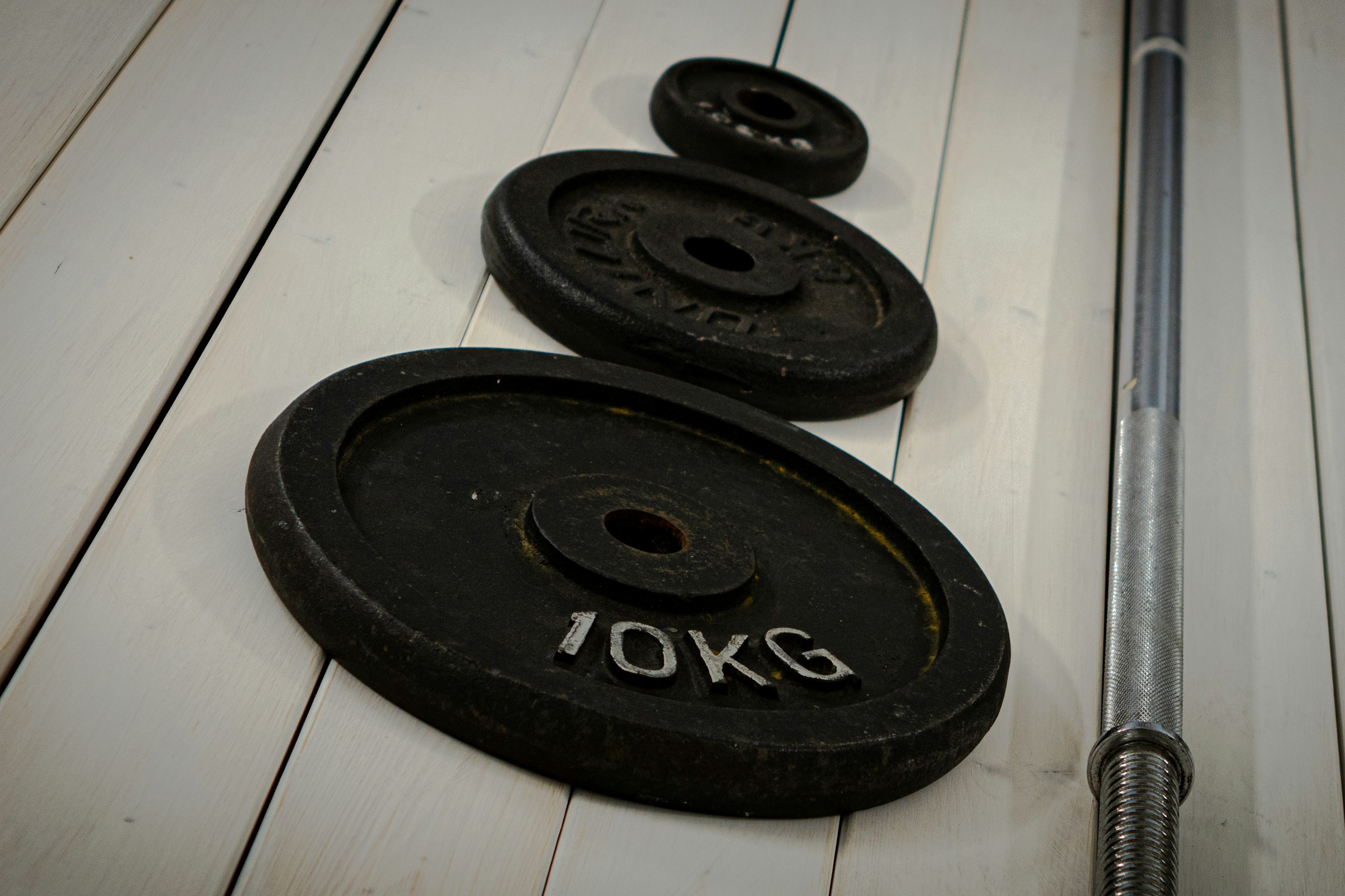 Iron weight plates and a bar lying on a pale floor