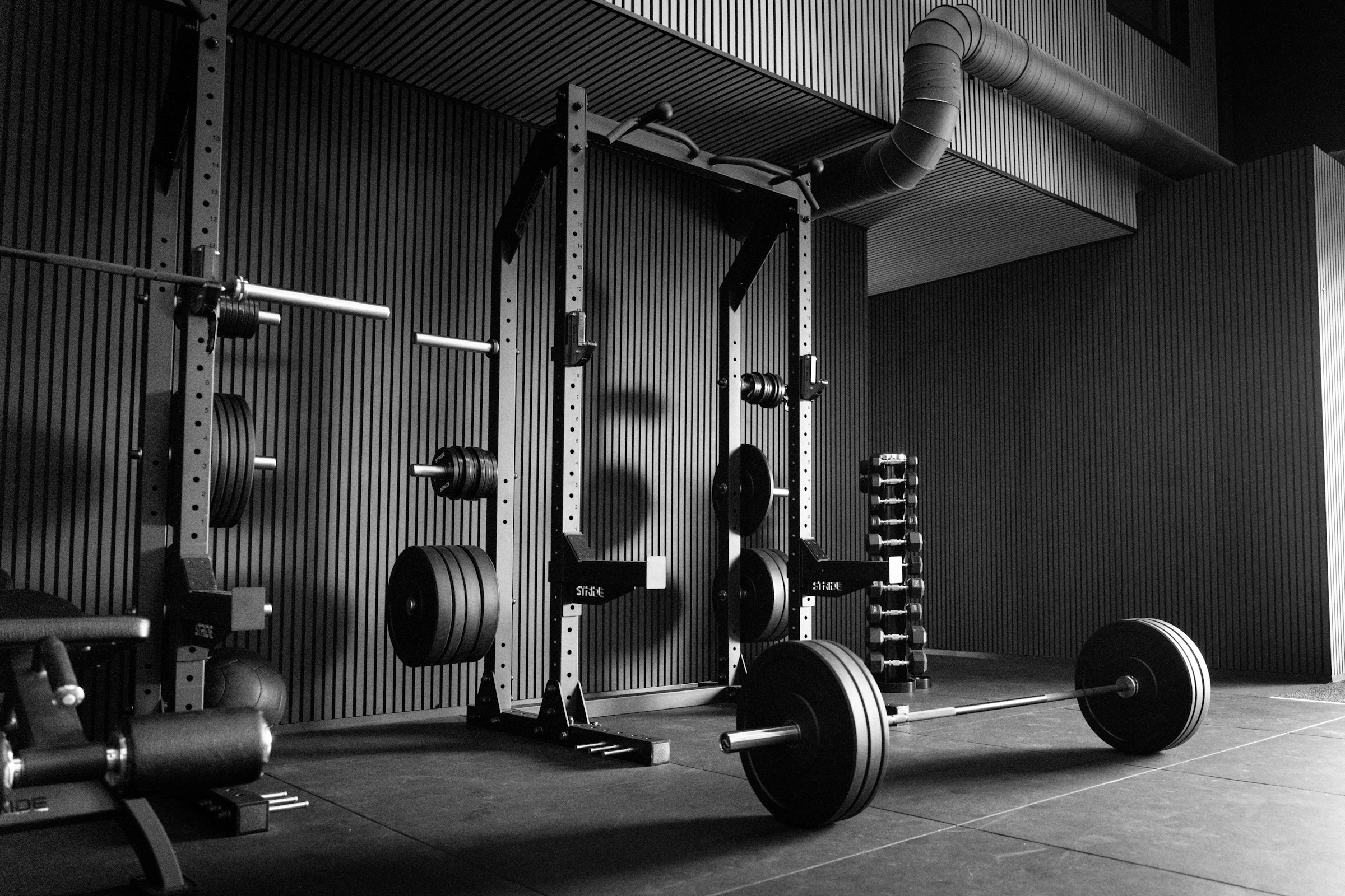 An empty power rack with a loaded barbell, in black and white