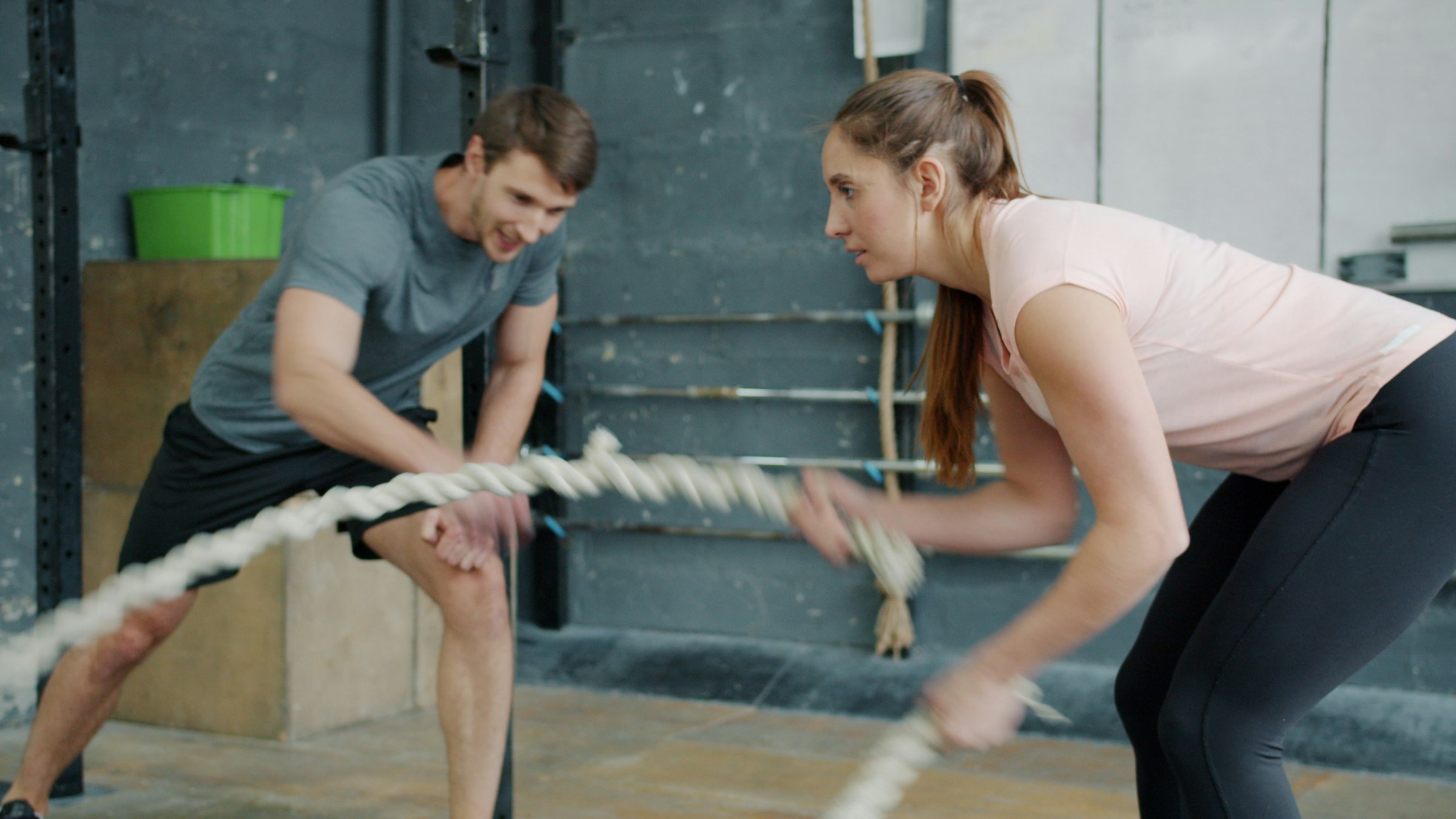 Two people working battle ropes in a gym